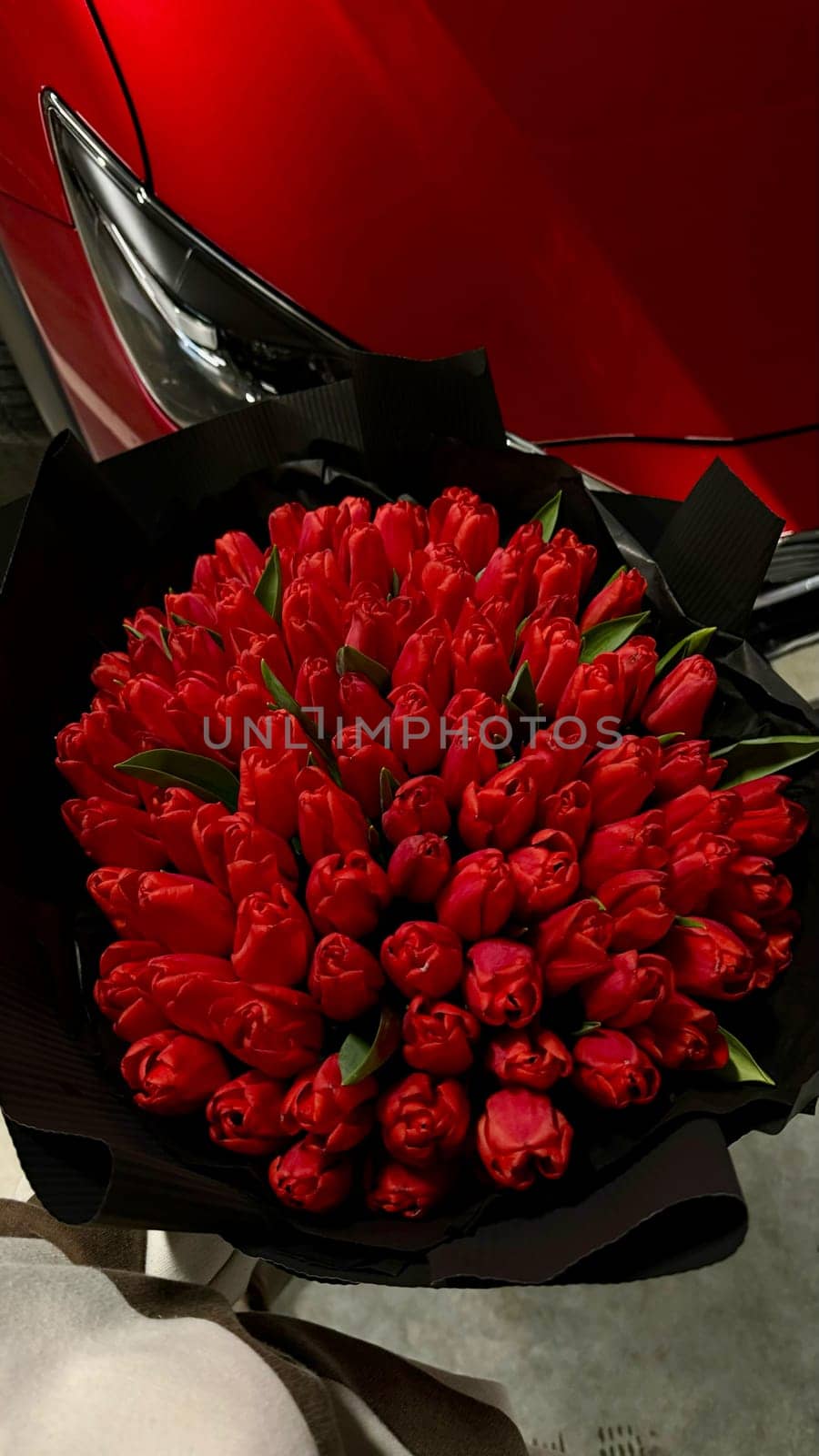 A large bouquet of bright red tulips on a red car. High quality photo