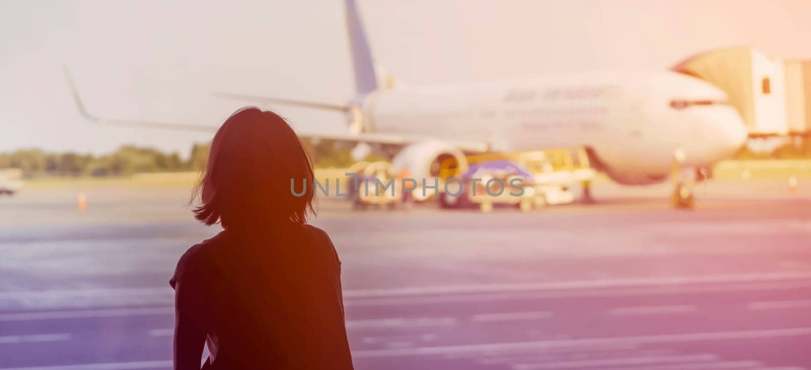A young girl at the airport is boarding a plane at sunset, a woman goes on a journey.
