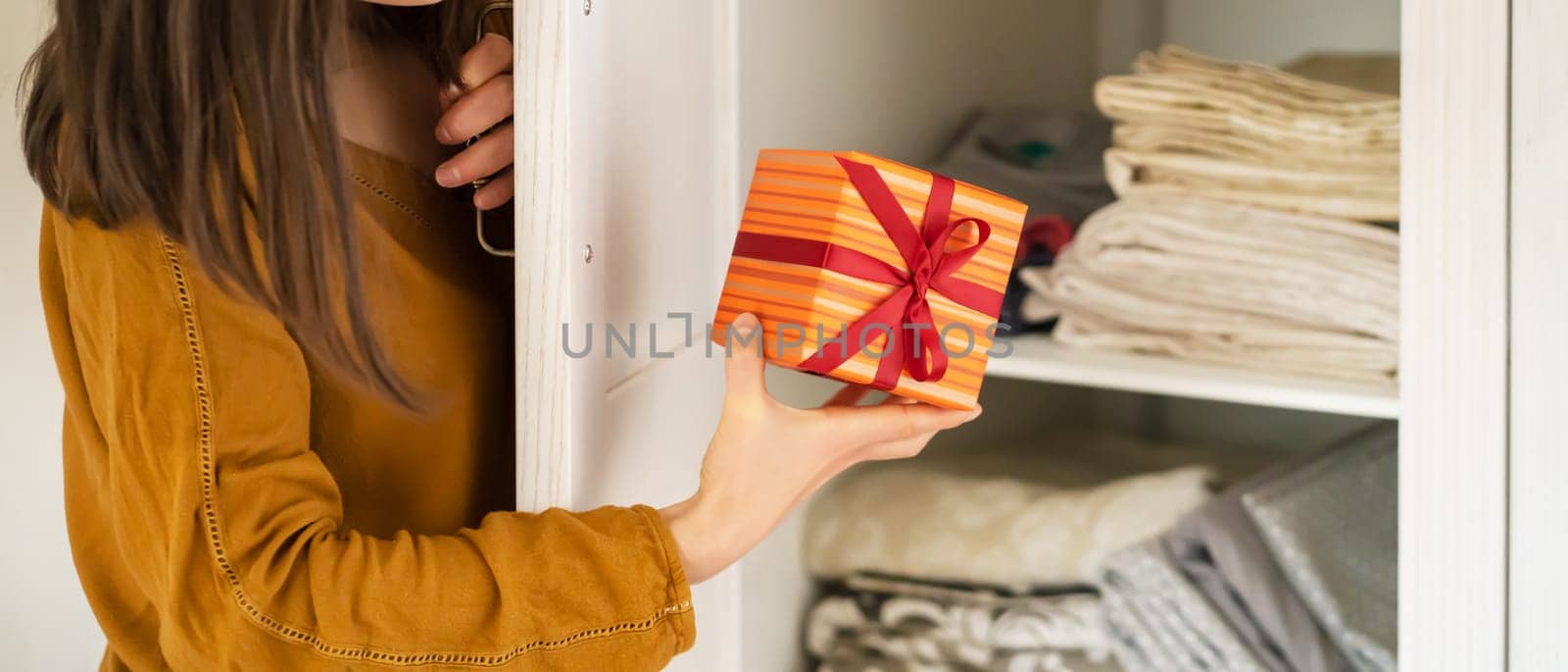 A funny young girl is in a hurry to hide a gift for a loved one, husband, children, friends and parents, a woman wants to make a surprise and hides the gift in the closet during holidays.