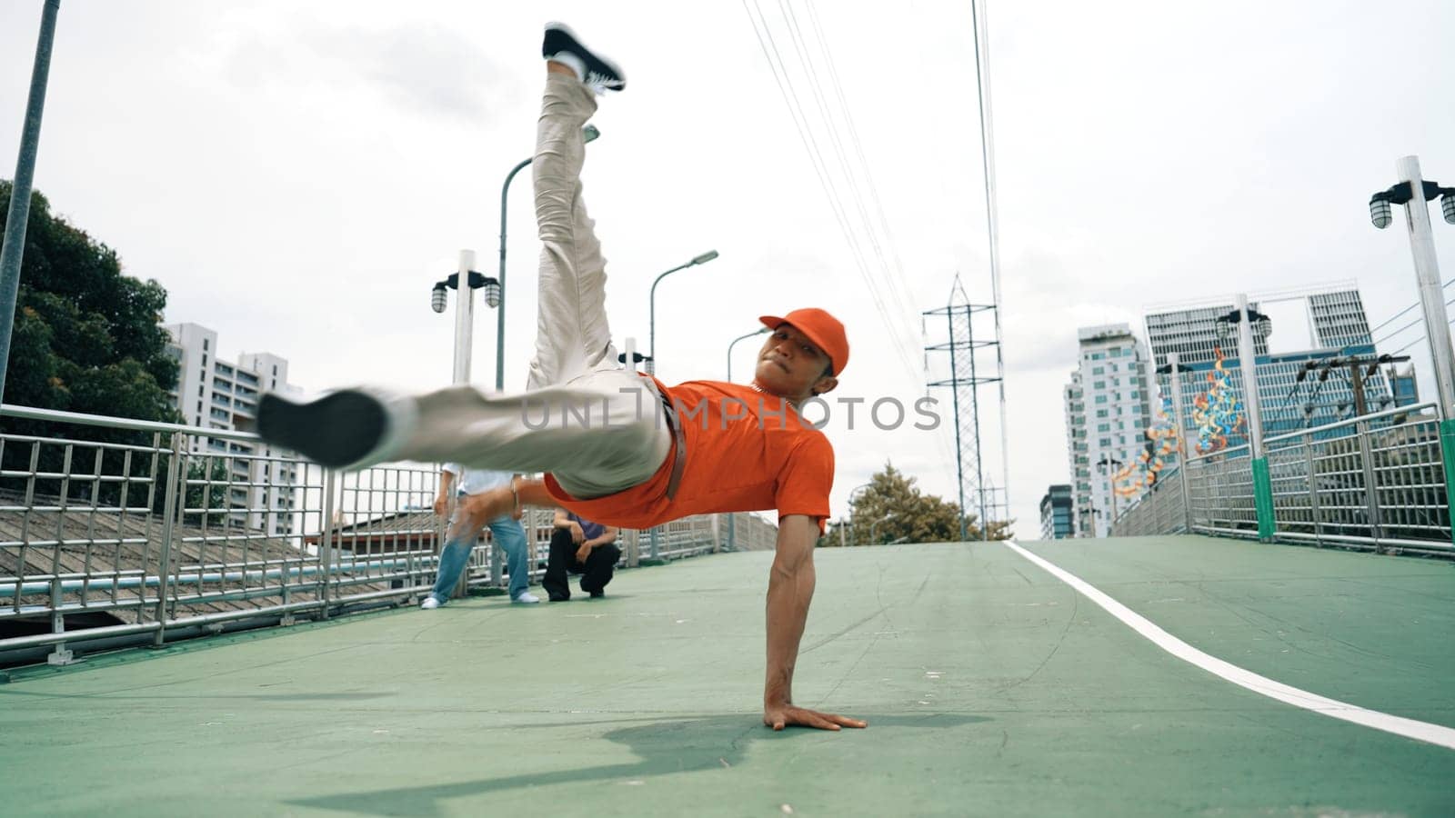 Young happy hipster perform break dancing or foot step with friend moving to hiphop music together. Skilled dancer doing freeze pose and waving hand. Modern lifestyle. Outdoor music 2024. Sprightly.