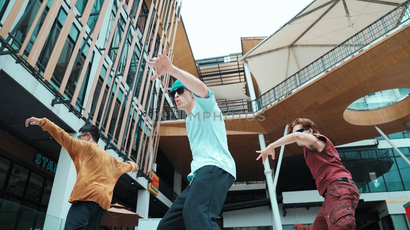 Caucasian group practice break dancing together. Energetic street dancer team in stylish fashion outfit perform hip-hop footstep at mall or city. Low angle view. Outdoor sport 2024. Endeavor.