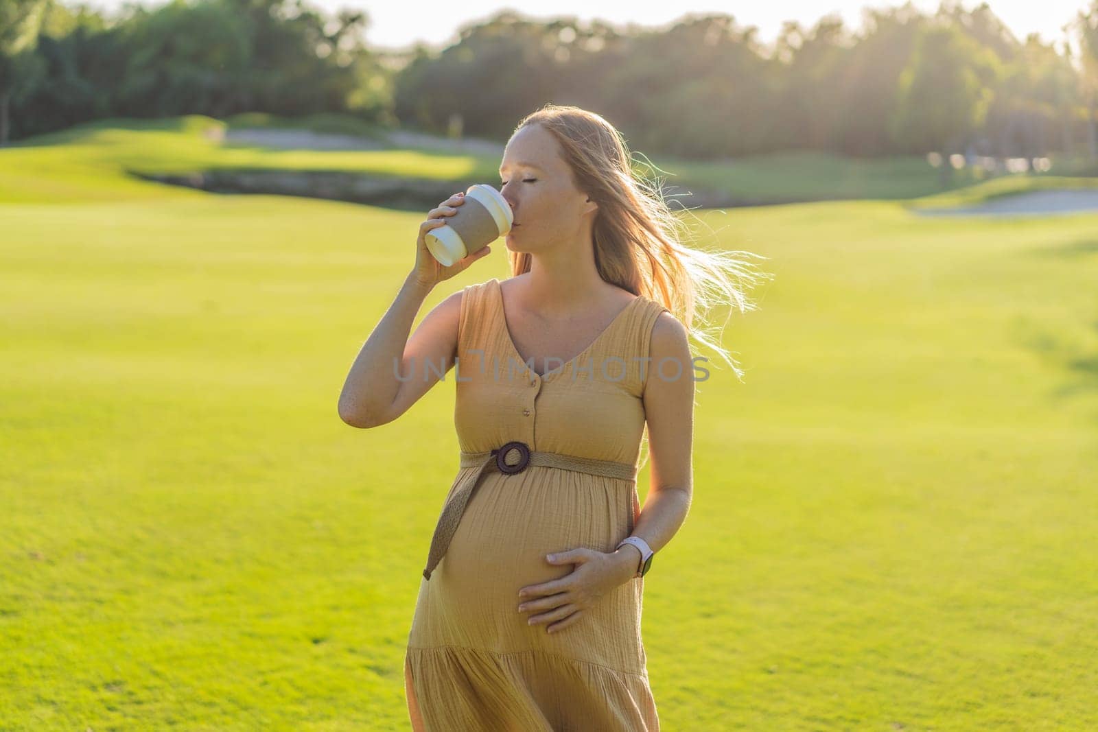 pregnant woman enjoys a cup of coffee outdoors, blending the simple pleasures of nature with the comforting warmth of a beverage during her pregnancy.