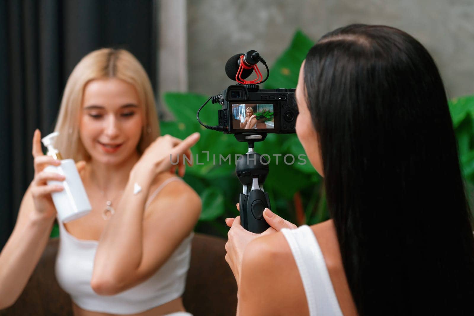 Two beautiful content creator making natural beauty and cosmetic tutorial on green plant leave garden video. Beauty blogger showing how to beauty care to social medial audience by selfie stick. Blithe