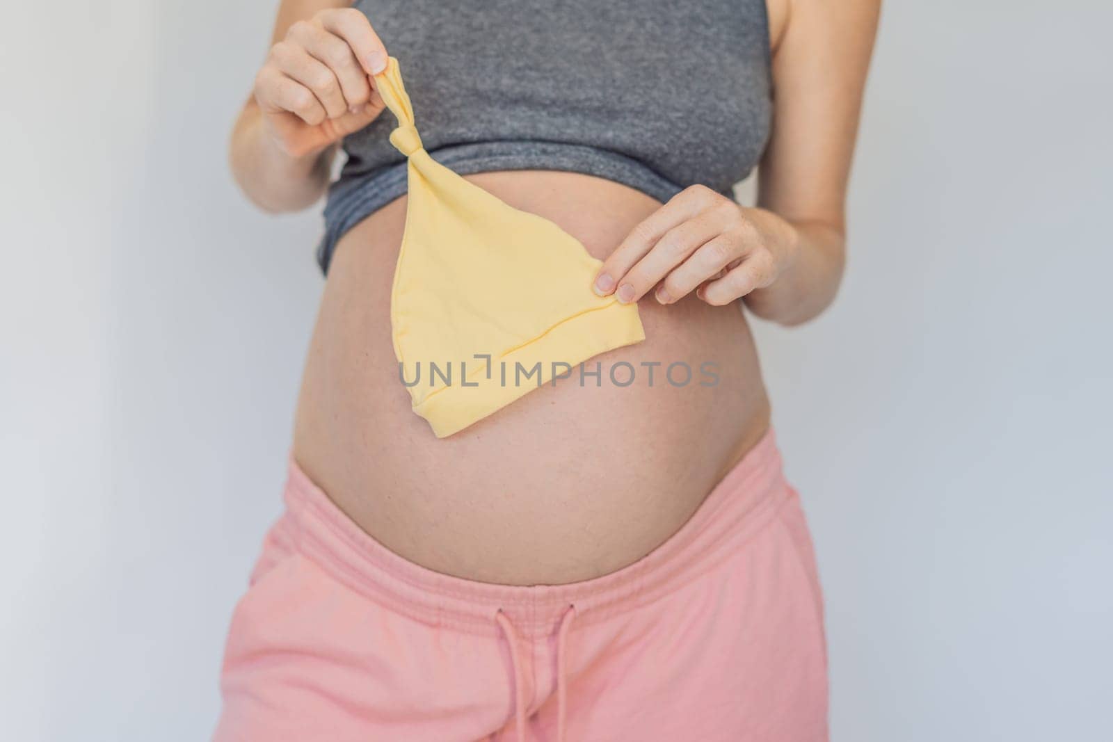 In a tender moment of anticipation, a pregnant woman cradles her unborn baby's clothes in her hands, savoring the sweetness of preparing for the little one's arrival.