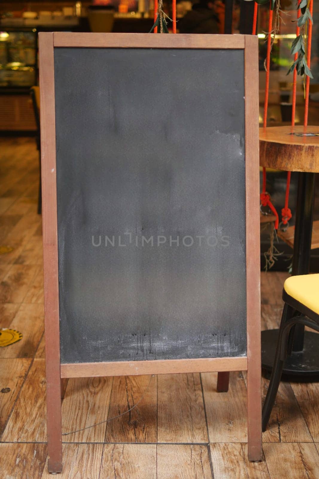 Empty wooden blackboard mockup standing outdoors in front of cafe .