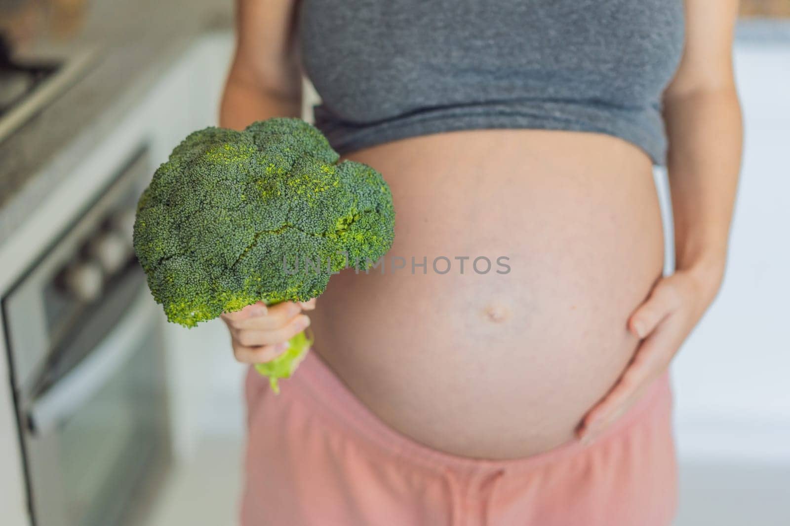 Embracing a nutrient-rich choice, a pregnant woman eagerly prepares to enjoy a wholesome serving of broccoli, prioritizing healthy and nourishing options during her pregnancy by galitskaya
