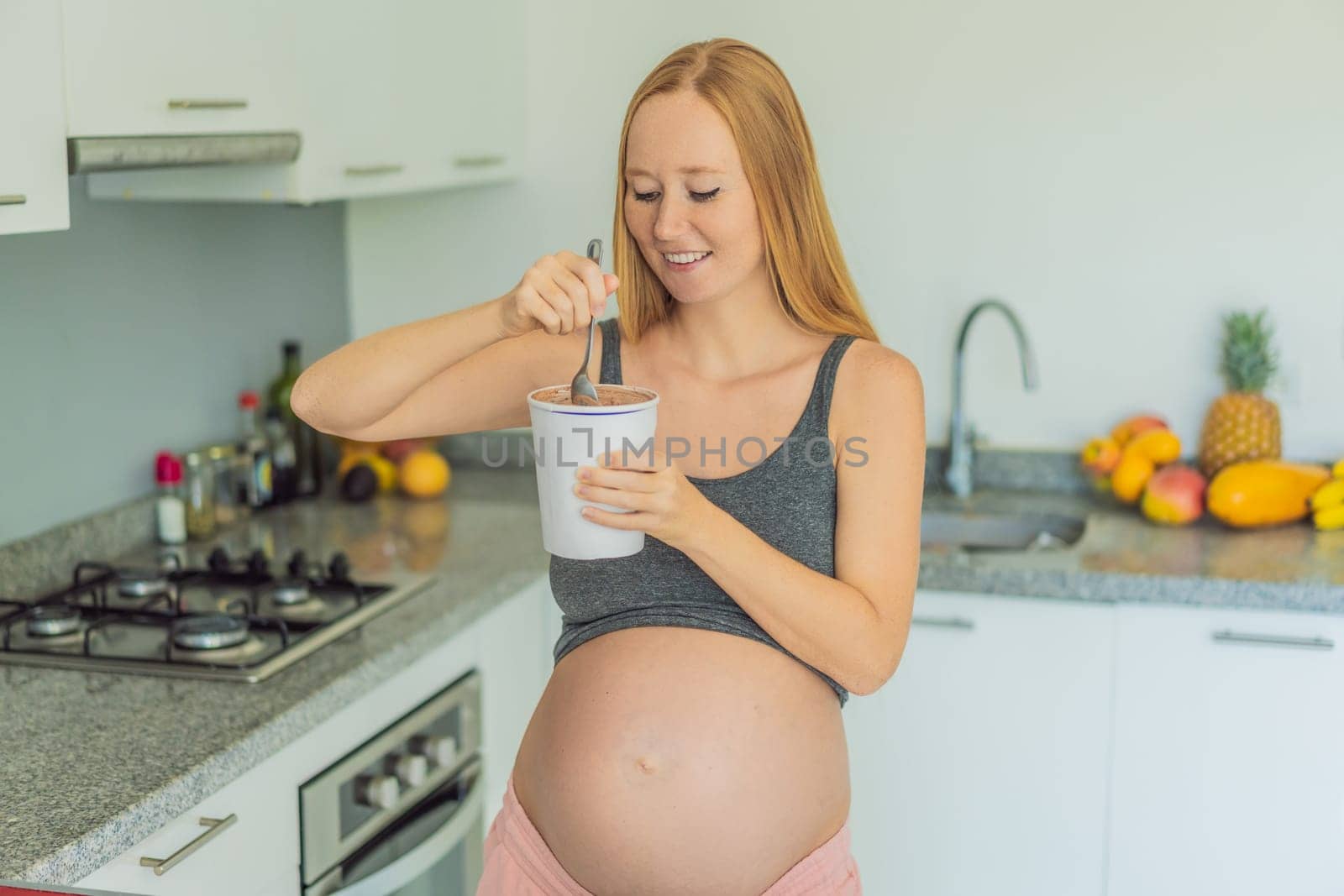 Happy pregnant young woman eating ice cream by galitskaya