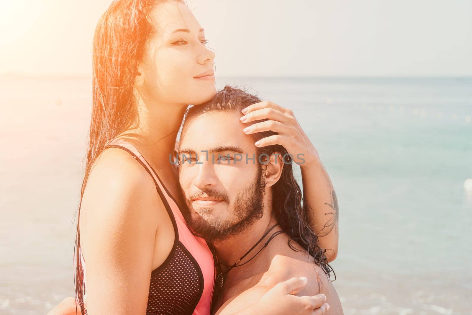 Close up shot of beautiful young caucasian woman with black hair and freckles looking at camera and smiling. Cute woman portrait in a pink bikini posing on a volcanic rock high above the sea