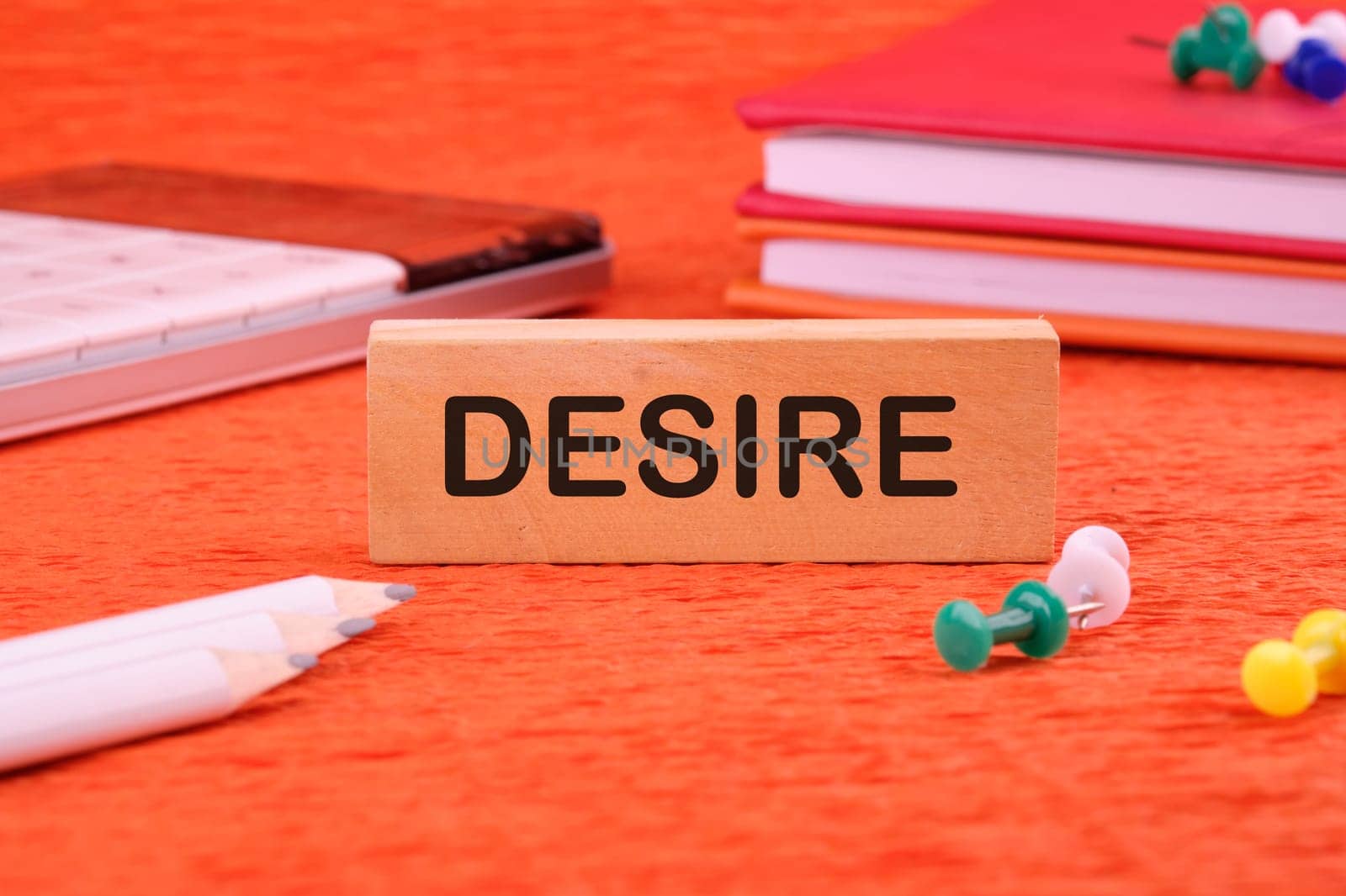 Desire text concept. DESIRE word, text written on a wooden block on an orange background next to office supplies