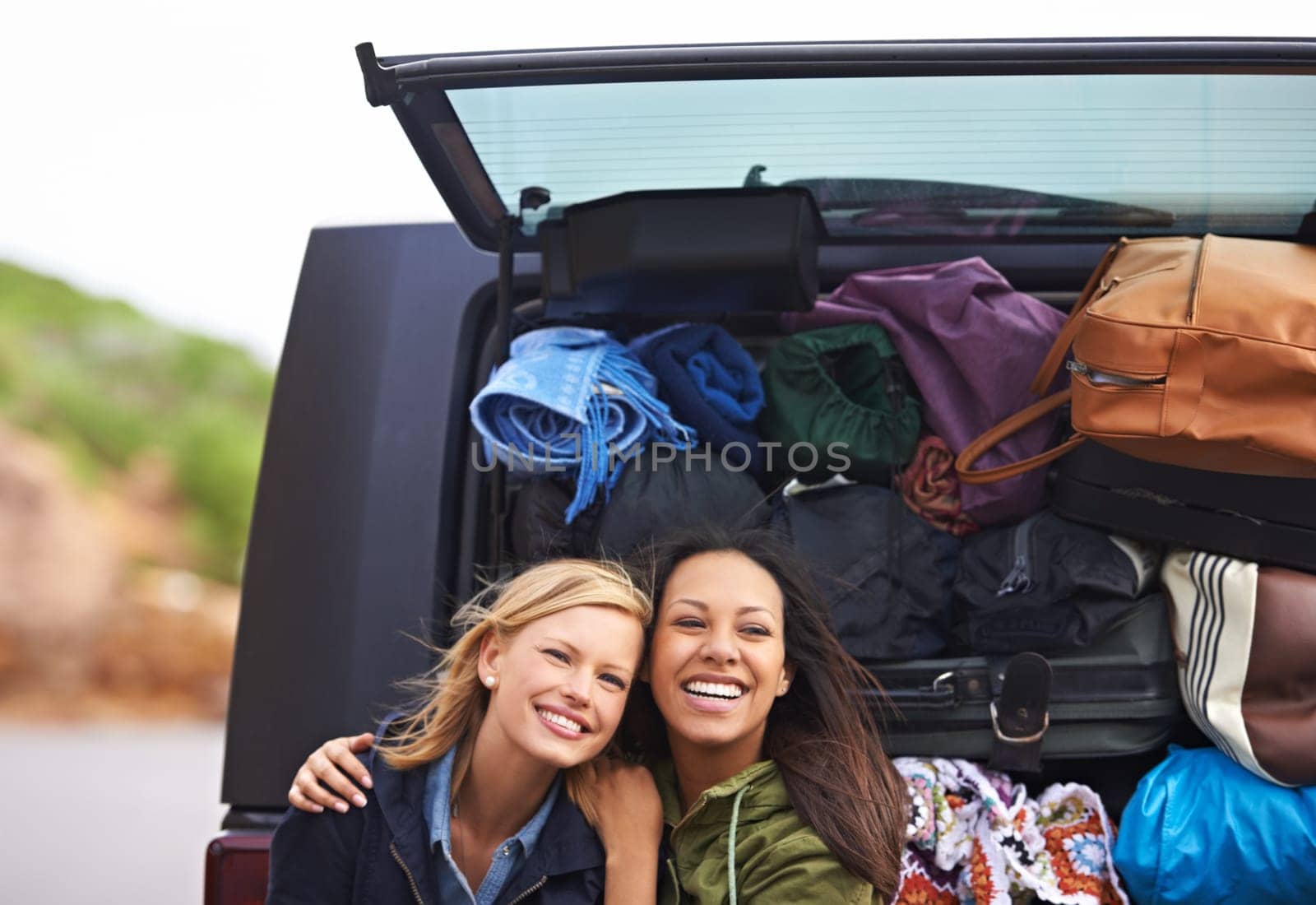 Women, friends and portrait on road trip with luggage in nature for camping holiday, vacation or explore. Female person, smile and car boot with bags for European adventure, transportation or journey.