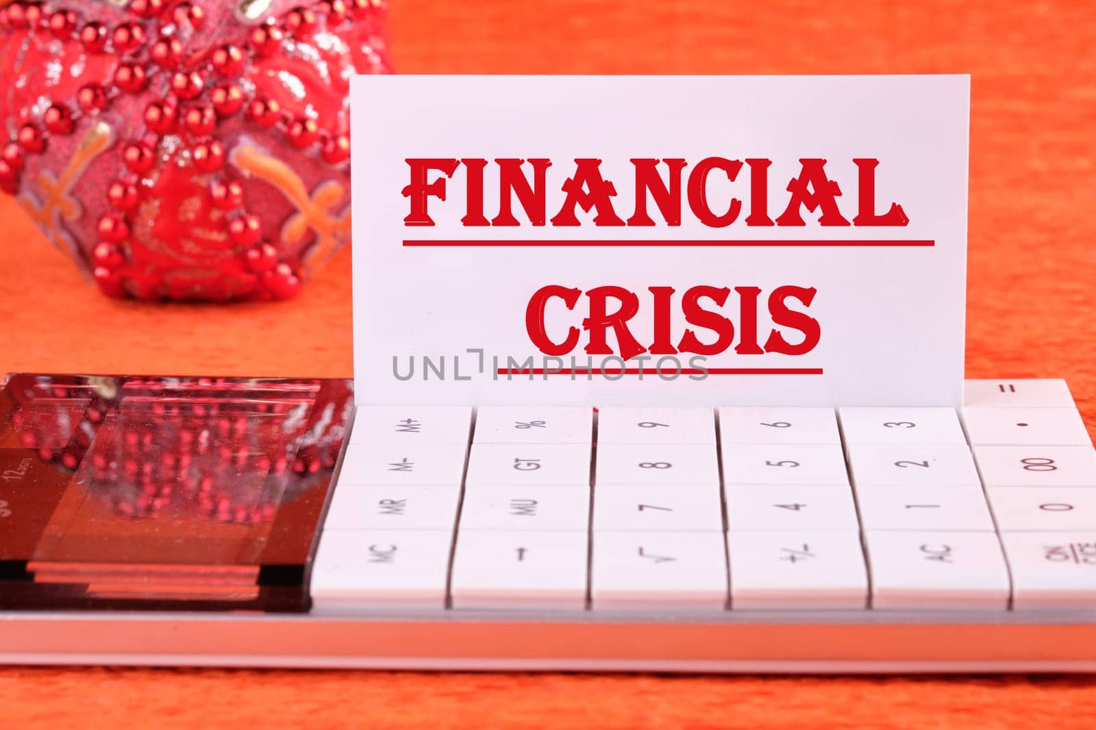 FINANCIAL CRISIS text written on a white business card on a calculator on an orange background by Ihar