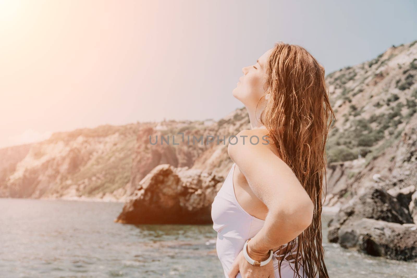 Woman travel sea. Happy tourist in white bikini enjoy taking picture outdoors for memories. Woman traveler posing on the beach at sea surrounded by volcanic mountains, sharing travel adventure journey by panophotograph