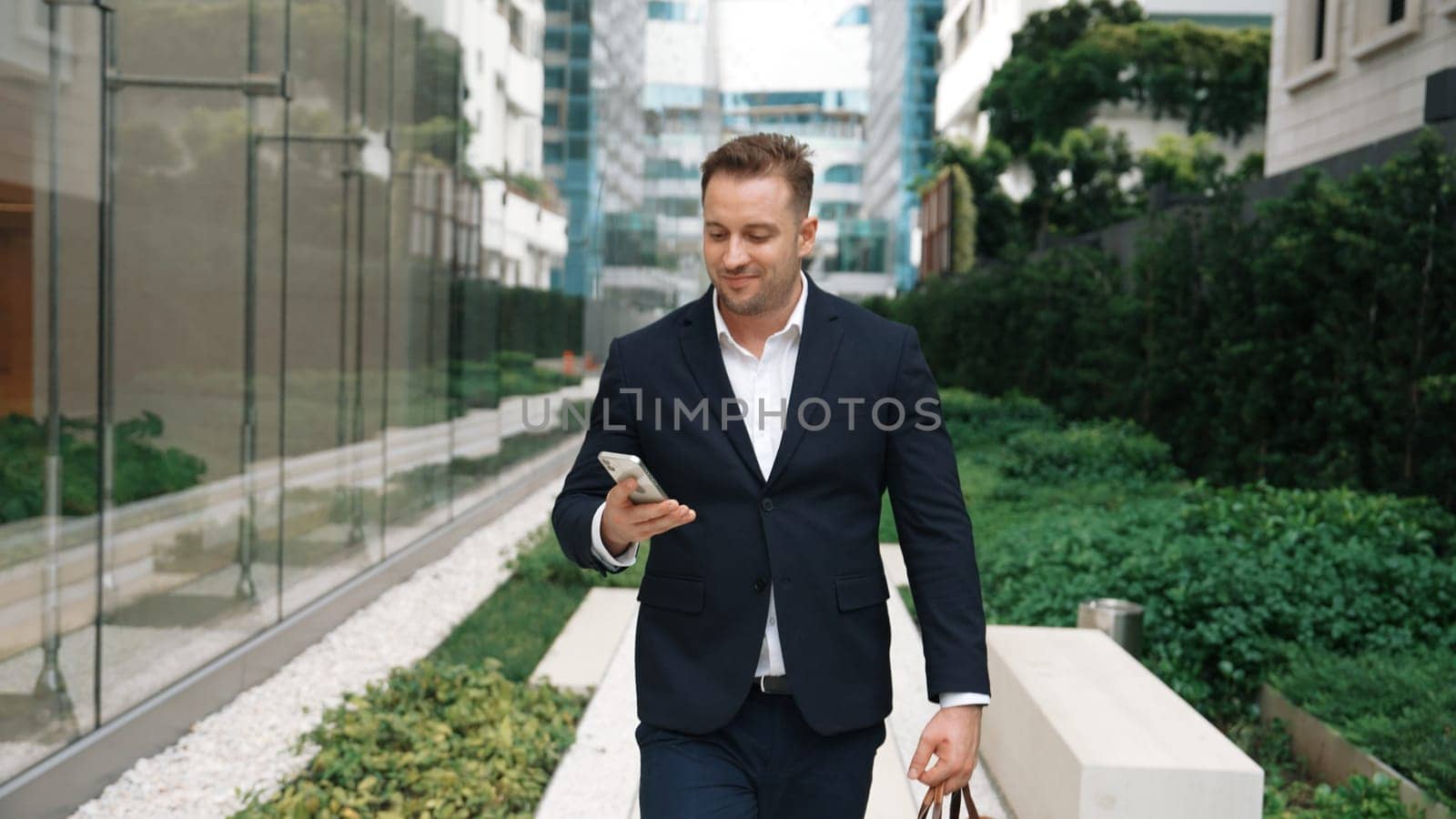 Businessman walking at park while talking to manager by using phone. Urbane. by biancoblue