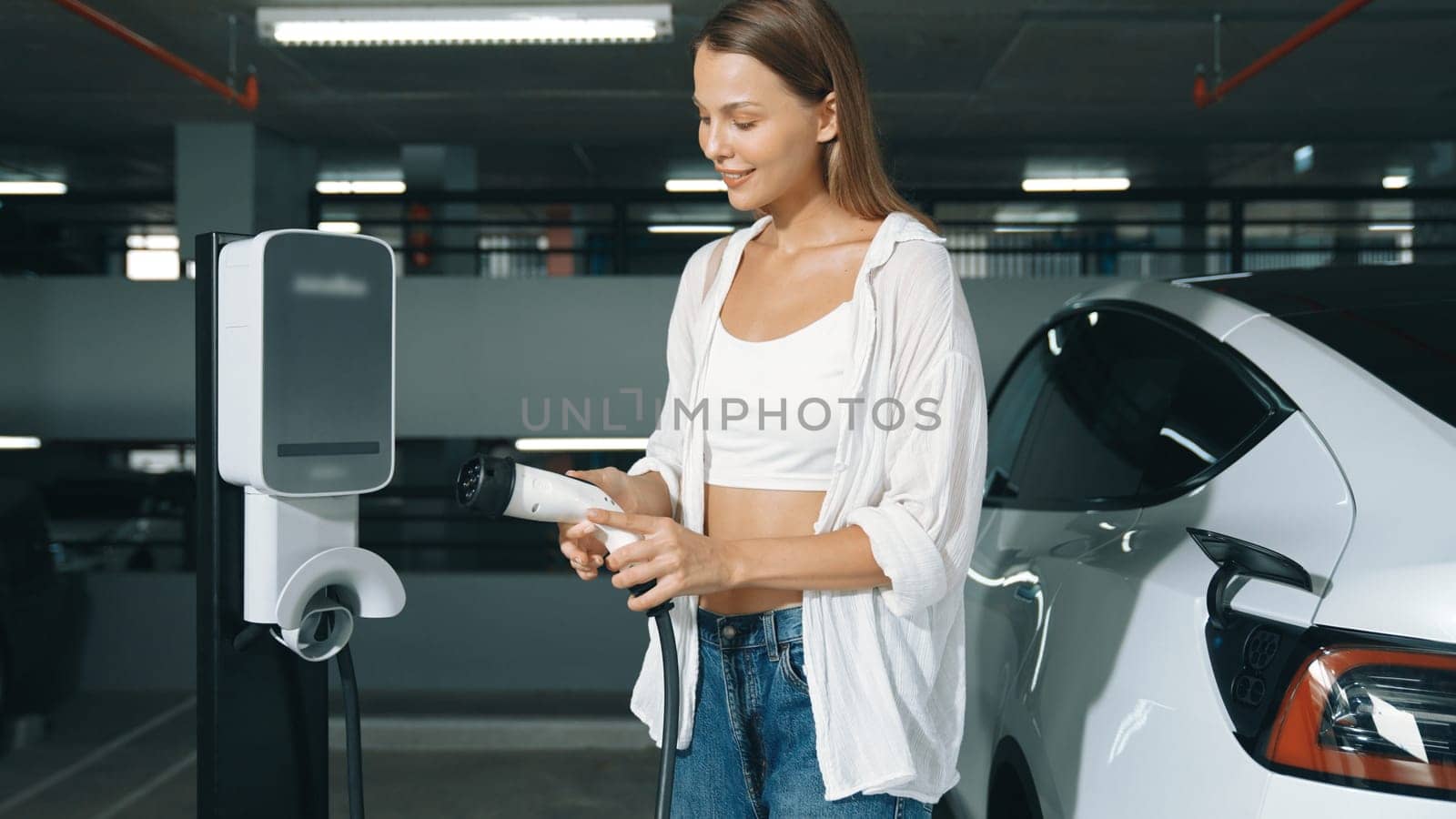Young motion woman travel with EV electric car to shopping center parking lot charging station in downtown city sustainability lifestyle by green clean rechargeable energy of electric vehicle innards