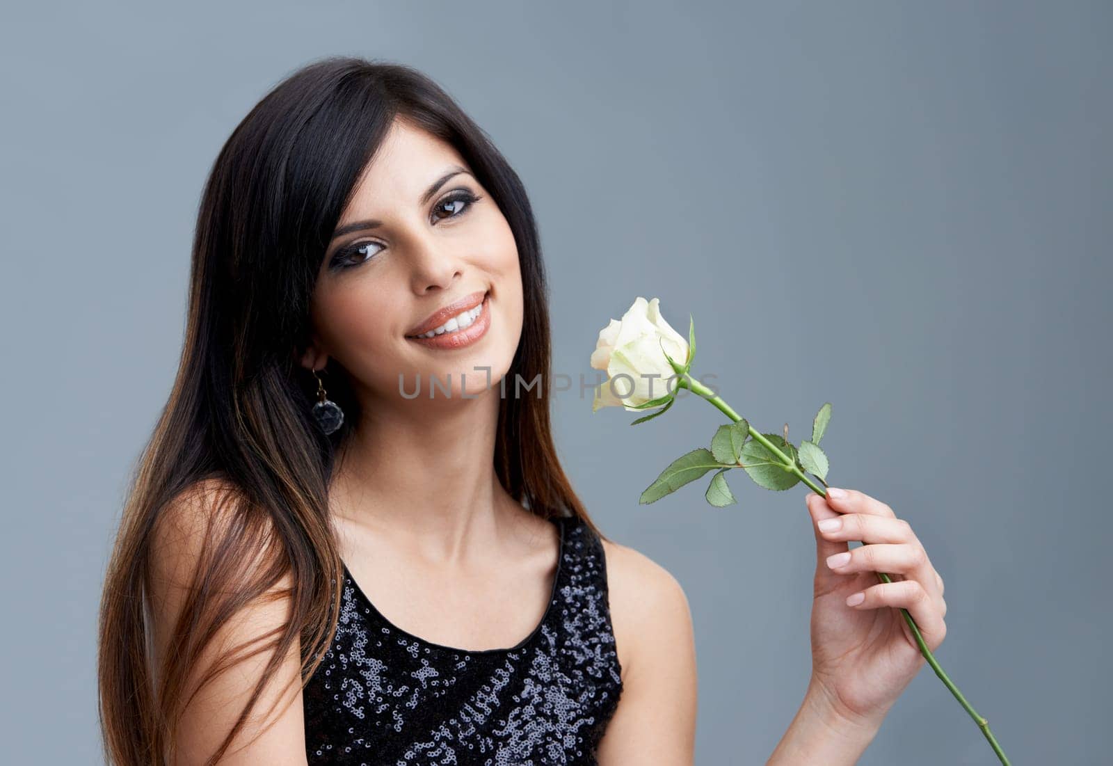 Fashion, flower and portrait of woman on gray background for beauty, cosmetics and confidence. Happy, smile and face of person with rose, floral and bloom for spring, romance and present in studio.