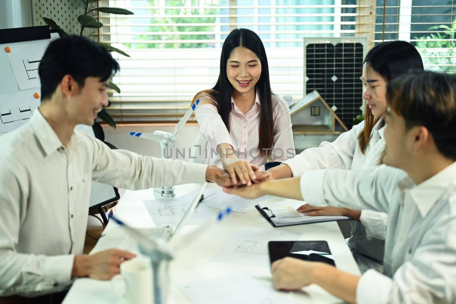 Architect team join hand together over meeting table for project development and innovation.