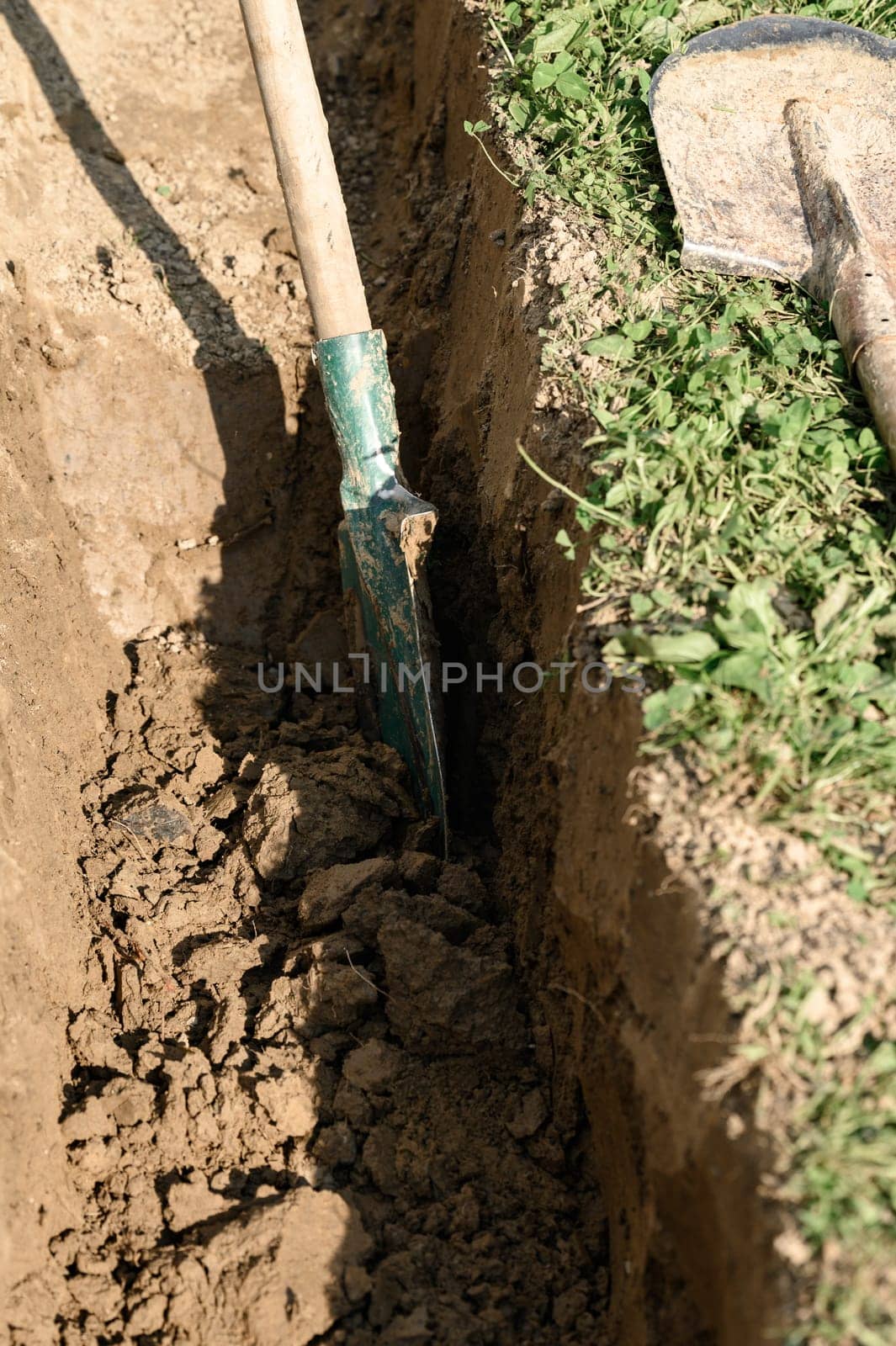 A man shovels a trench for drainage and sewage, close up.
