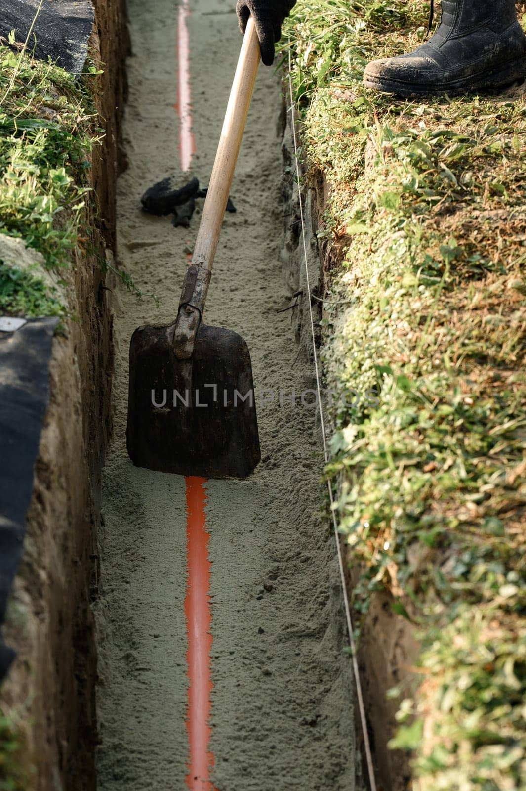 Plumber installs a reinforced orange sewer pipe during site maintenance. by Niko_Cingaryuk
