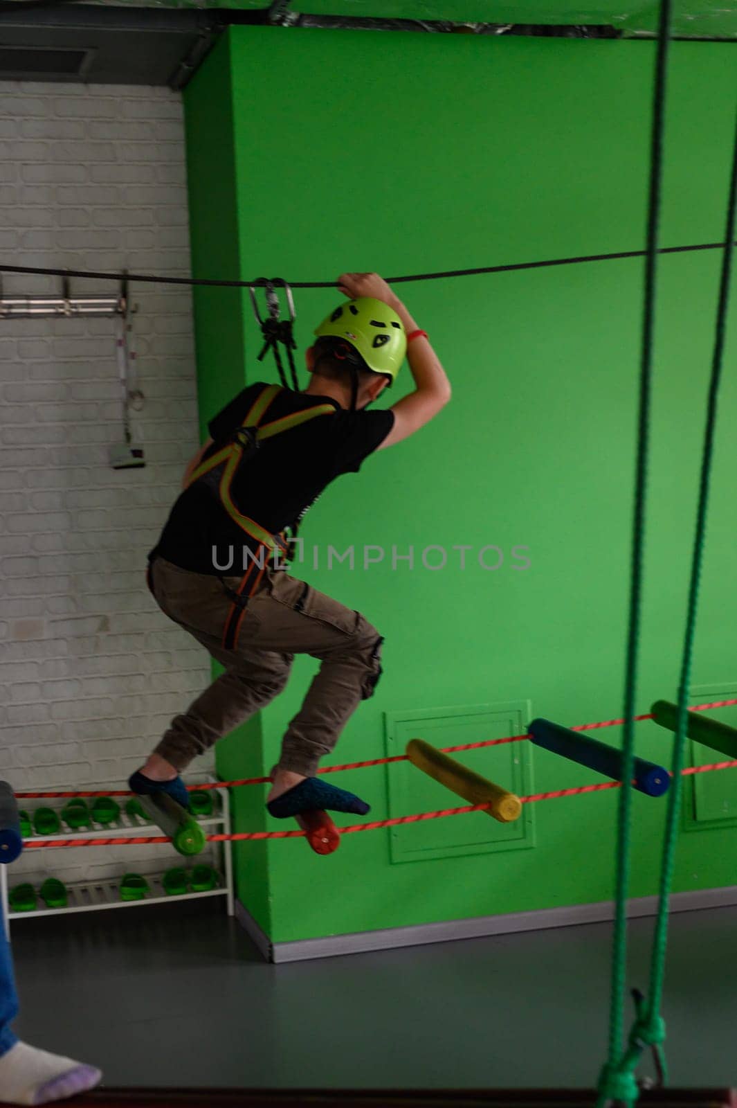 The boy actively and attentively passes the ropeway in the playroom. by Niko_Cingaryuk