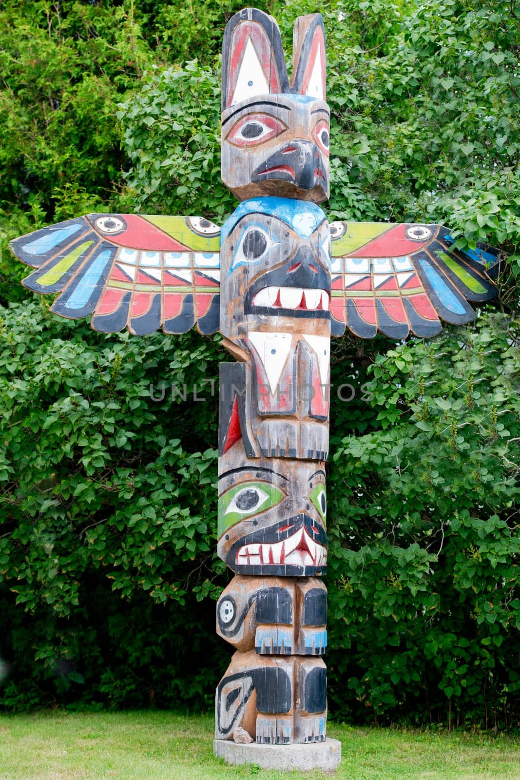 Isolated totem wood pole in the green forest background