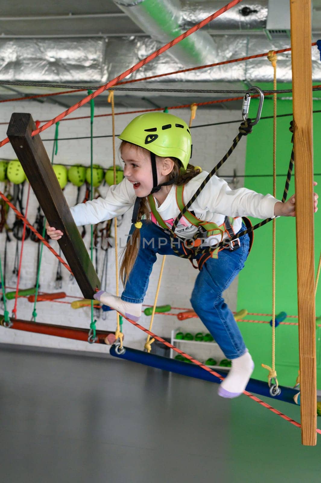 The girl carefully and carefully passes the cableway in the playroom, active recreation for children.