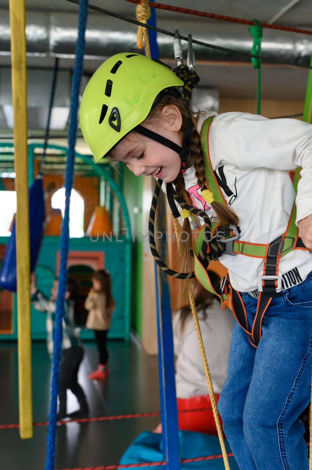 Happy girl passes the cableway, active recreation in the playroom, cableway for the physical development of the child.