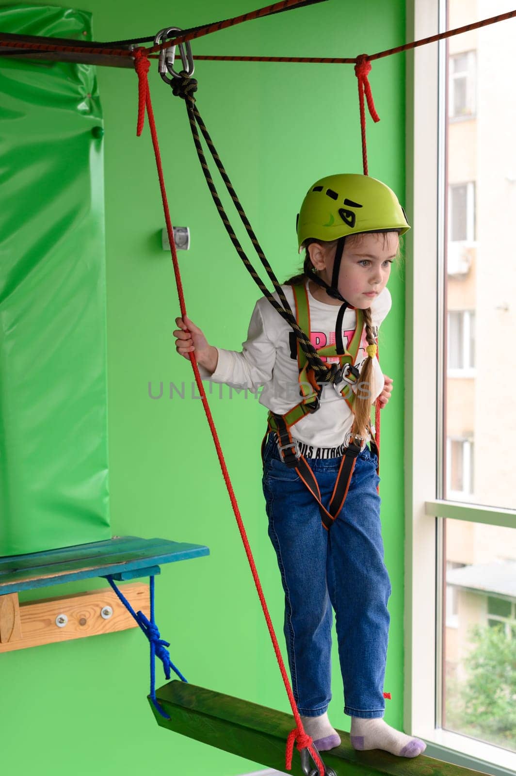 Children's cableway in the playroom, little girl passes the cableway, active and physical development of the child.