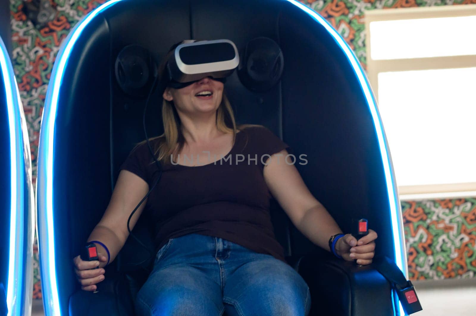 Virtual reality attraction, virtual glasses and entertainment in playrooms for children. A woman sits in a 5d neon chair. by Niko_Cingaryuk