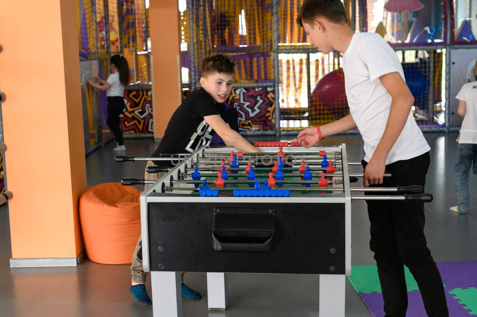Two boys are playing table football in the playroom by Niko_Cingaryuk