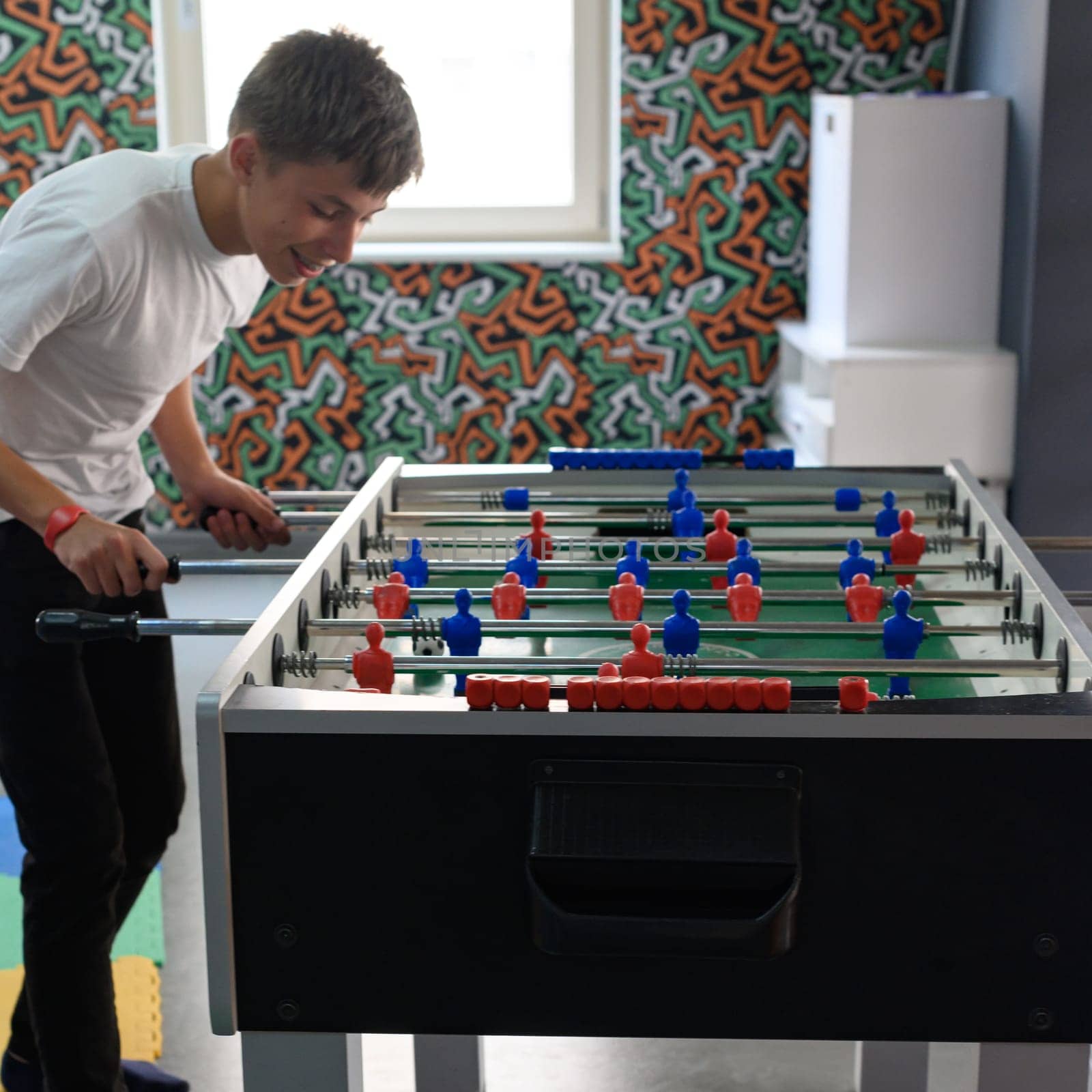 Active recreation in the game room, children play table football. by Niko_Cingaryuk