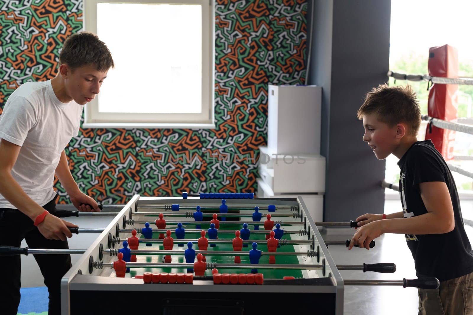 Active recreation in the game room, children play table football. by Niko_Cingaryuk
