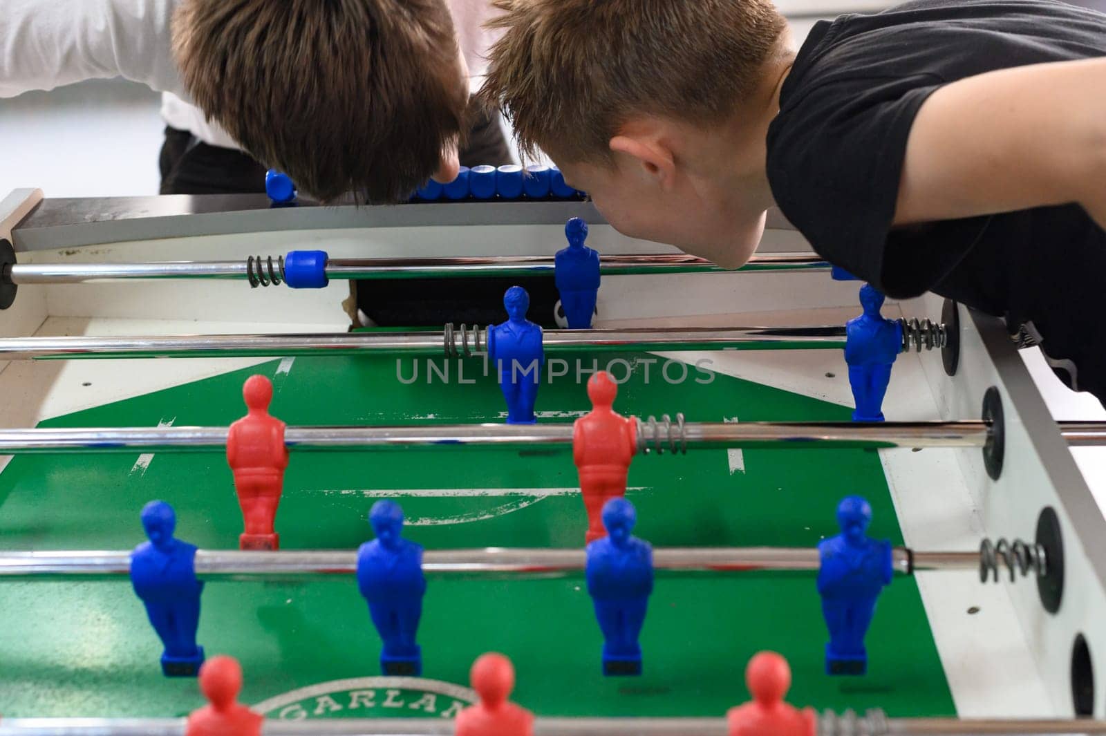 Active recreation in the game room, children play table football, active game for children.