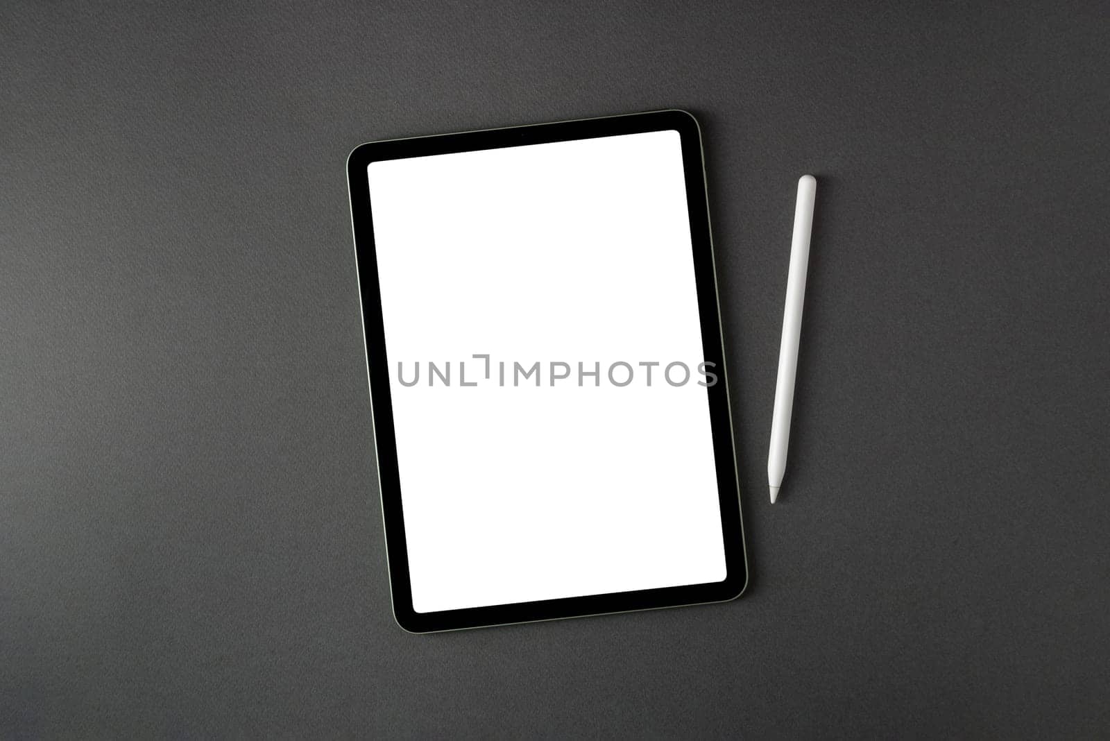 Tablet with blank screen and stylus on dark gray office desk by Sonat