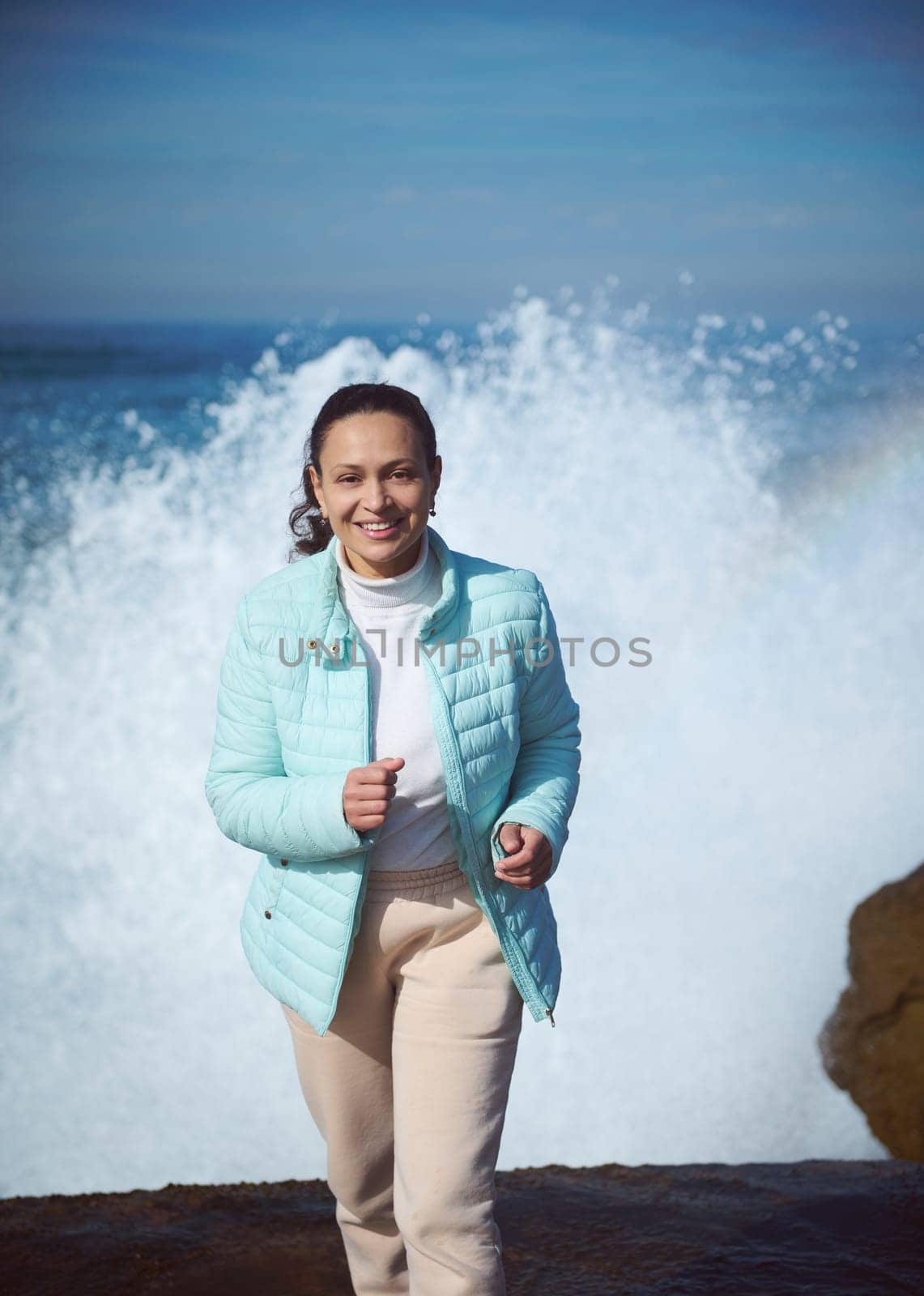 Running woman against huge wave on the Atlantic ocean, People and nature