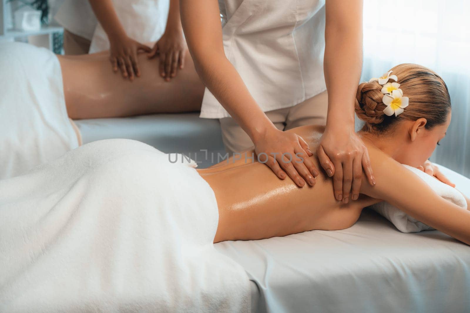 Caucasian couple customer enjoying relaxing anti-stress spa massage and pampering with beauty skin recreation leisure in day light ambient salon spa at luxury resort or hotel. Quiescent