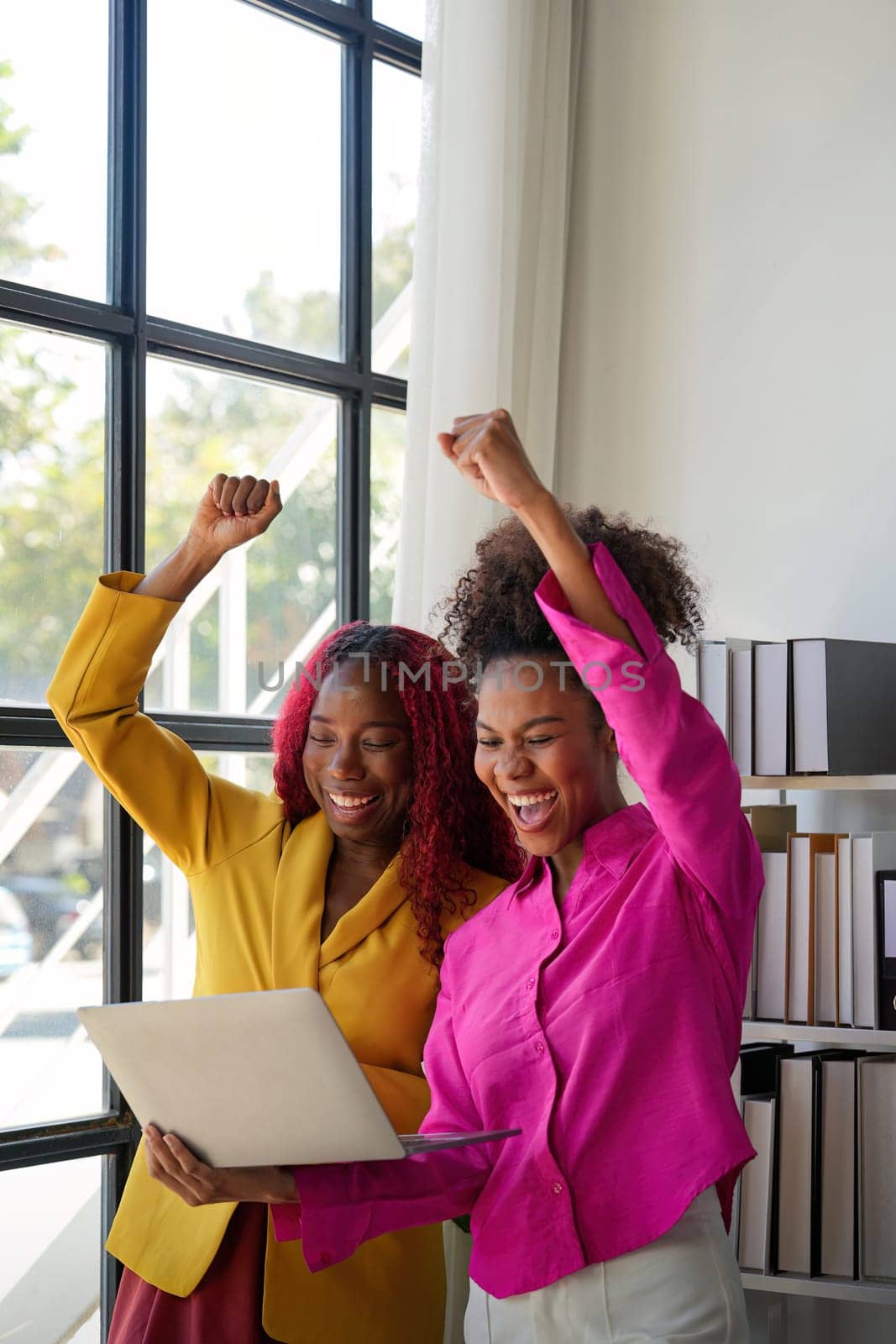 Two african woman celebrate when business goal success. achievement and business goal success concept by nateemee