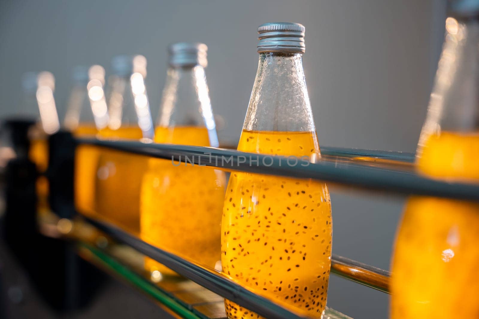 Basil or chia seed beverages with pomegranate undergo quality filling into transparent bottles by Sorapop