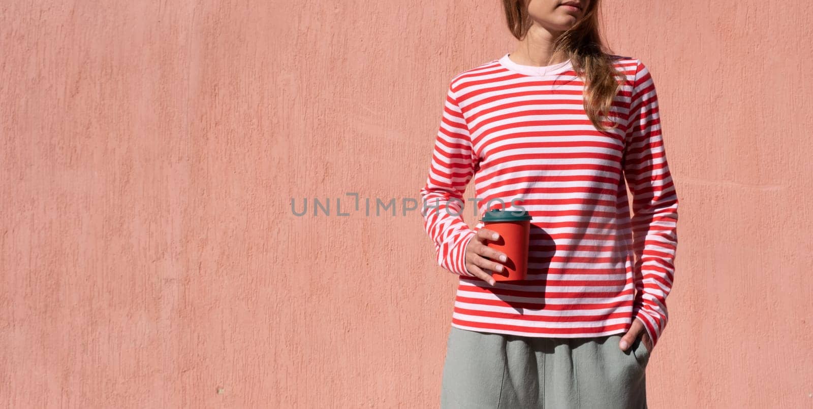 Woman in striped shirt holding red cup and drinking coffee by Desperada