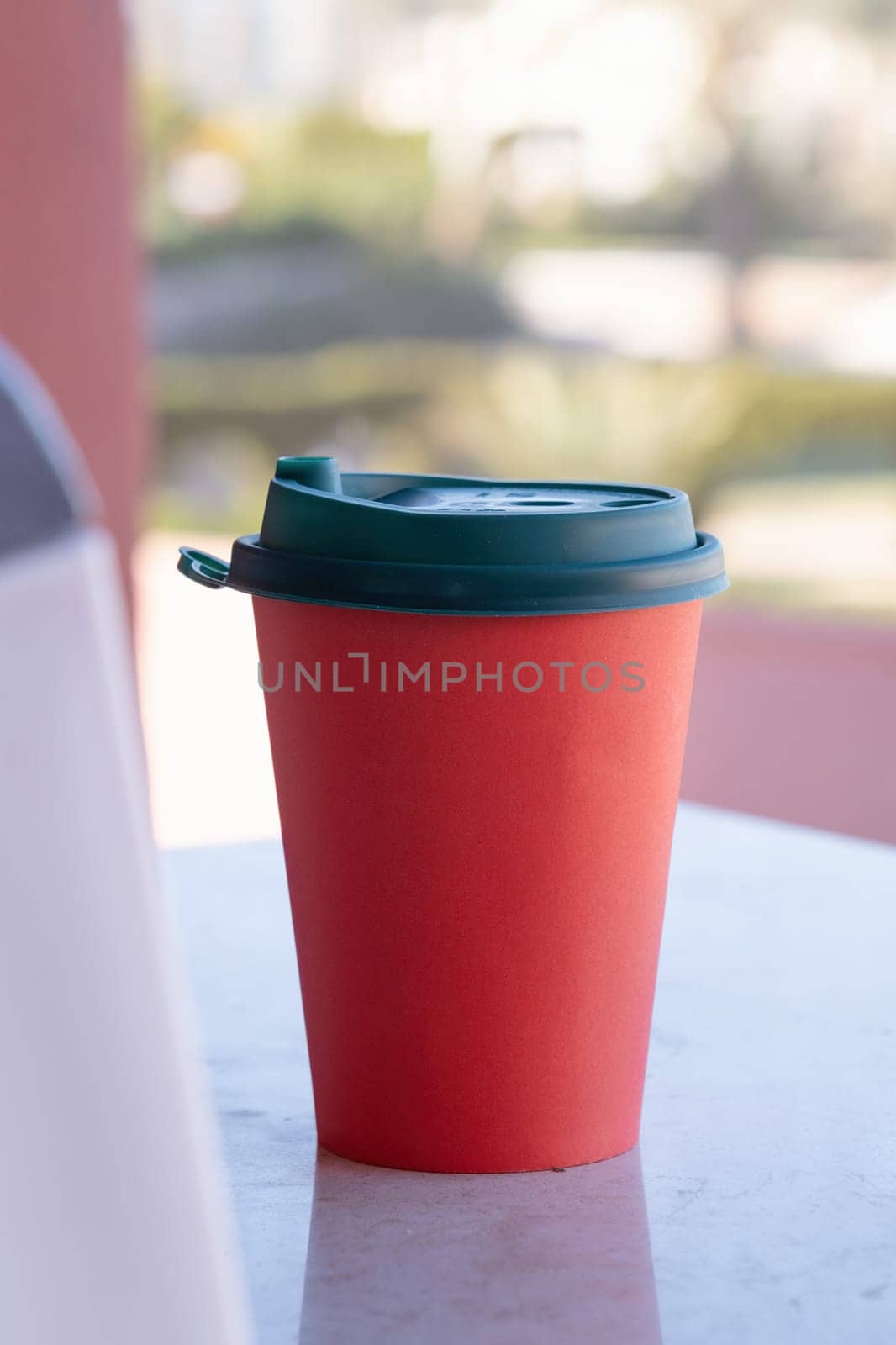 red paper coffee cup on coffee table in the balcony. mockup design, natural light