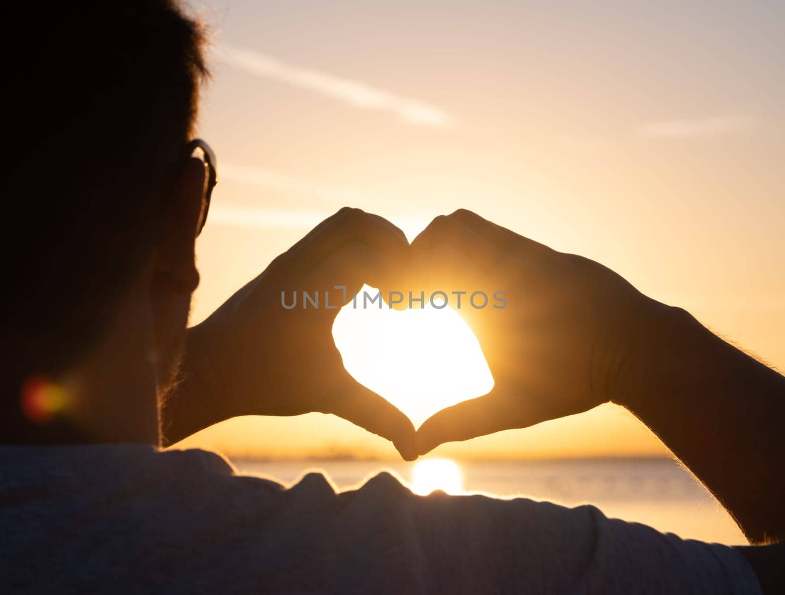 man hands forming a heart shape with sunset silhouette by Desperada