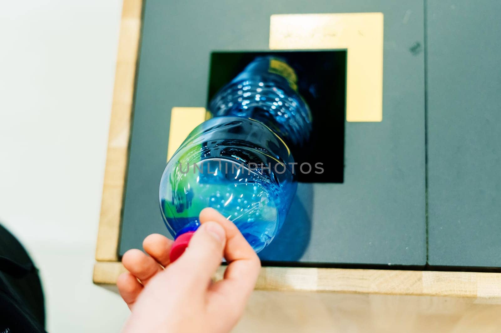 Close up hand throwing empty plastic water bottle into recycling bin, recycle rubbish by Zelenin