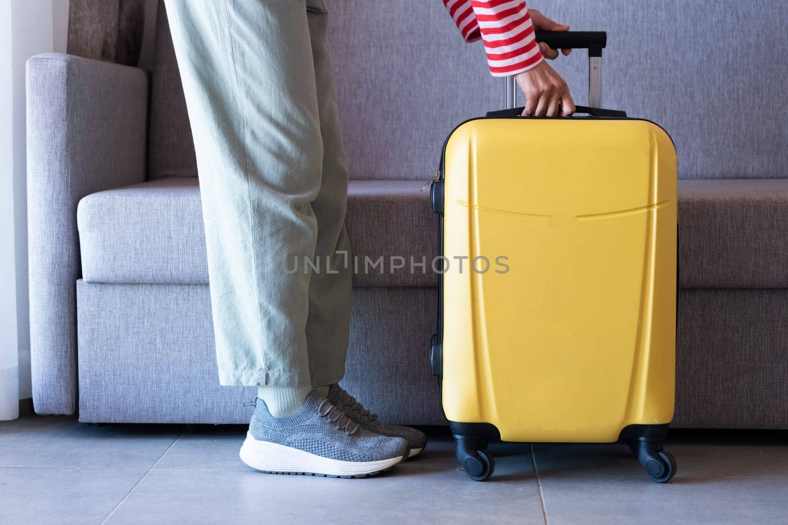 yellow suitcase and woman legs on sofa background in hotel room