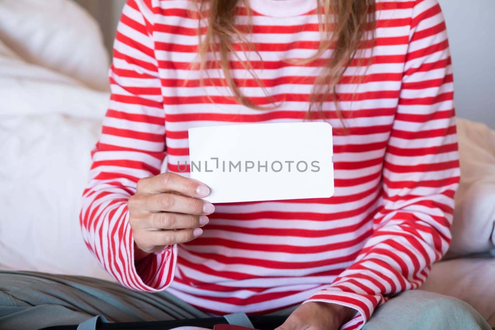 woman preparing for holidays, packing suitcase on bed, woman holding a blank boarding pass by Desperada