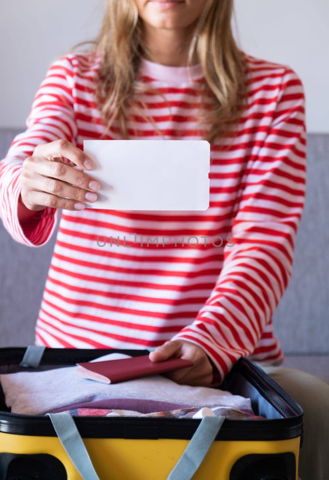 woman preparing for holidays, packing suitcase on bed, woman holding a blank boarding pass by Desperada