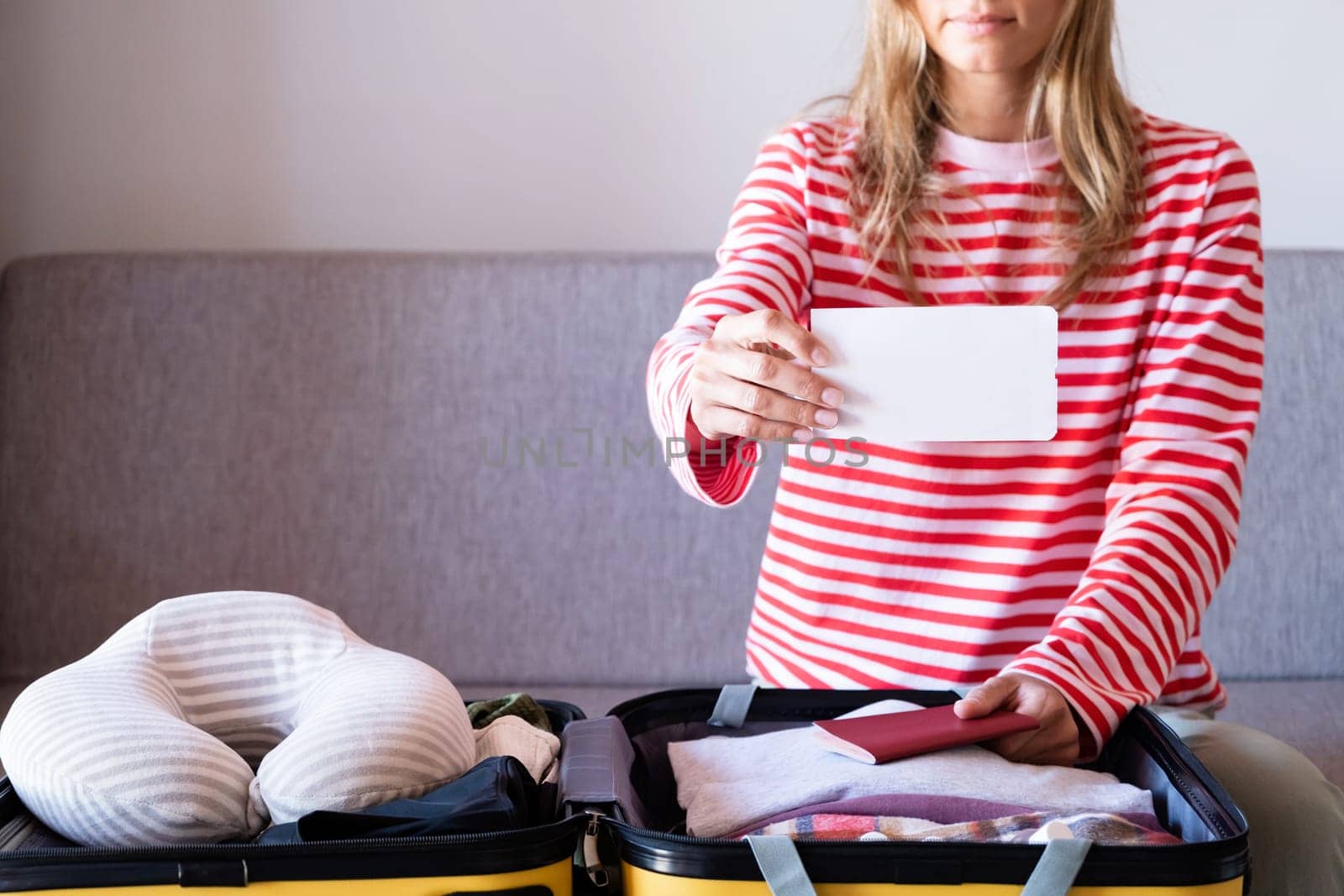 woman preparing for holidays, packing suitcase on bed, woman holding a blank boarding pass by Desperada