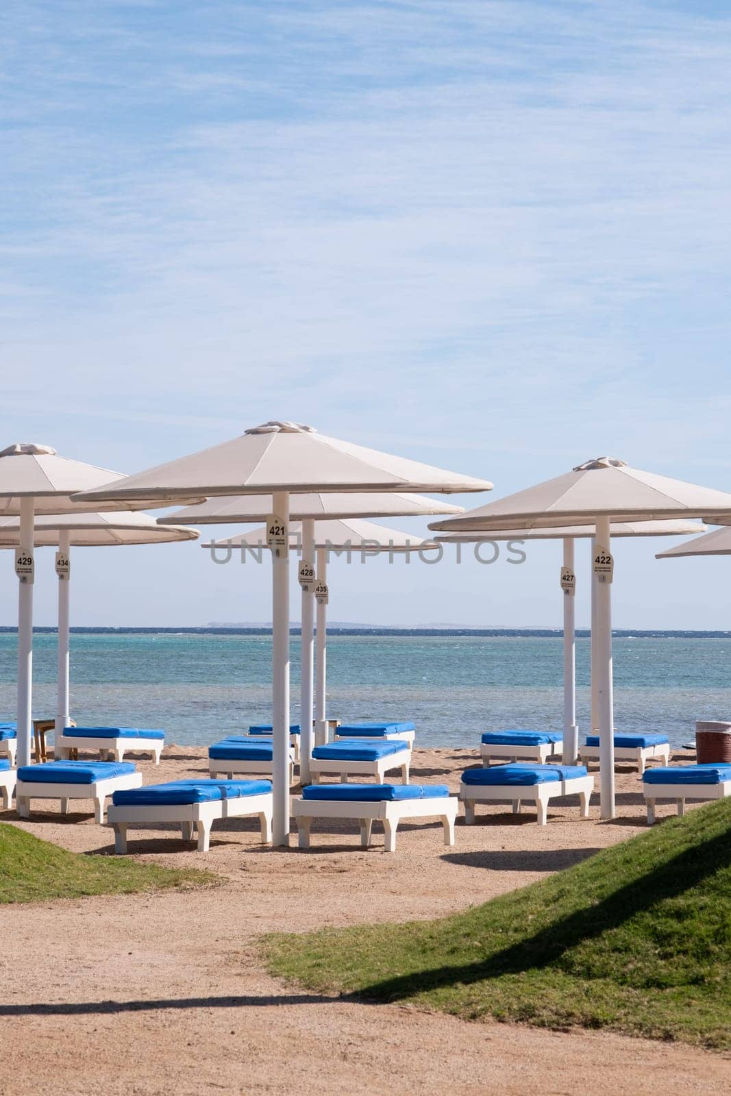 Empty beach with umbrellas and sun loungers by Desperada