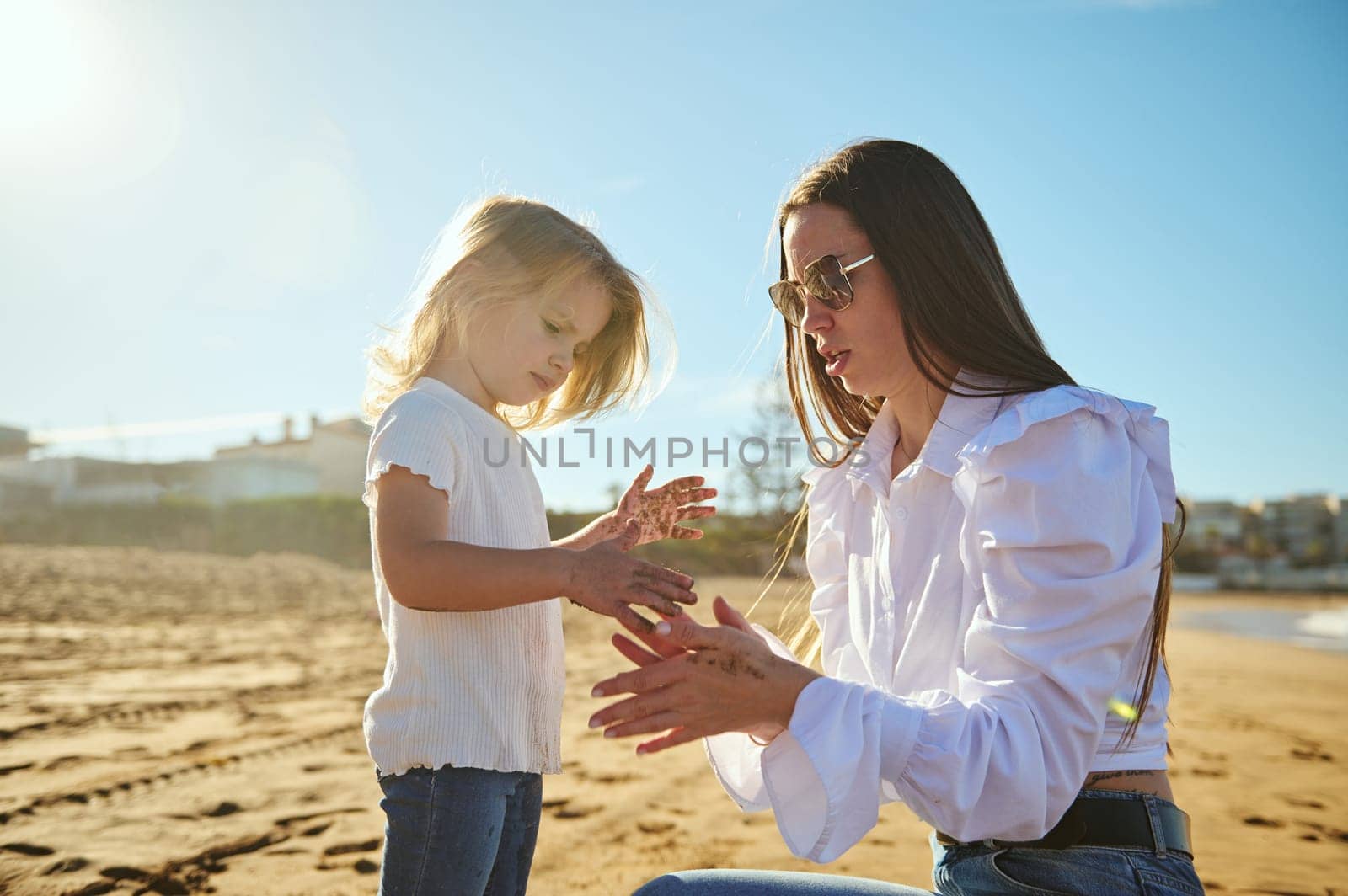 Mom and lovely daughter playing together on the sandy each on a sunny day