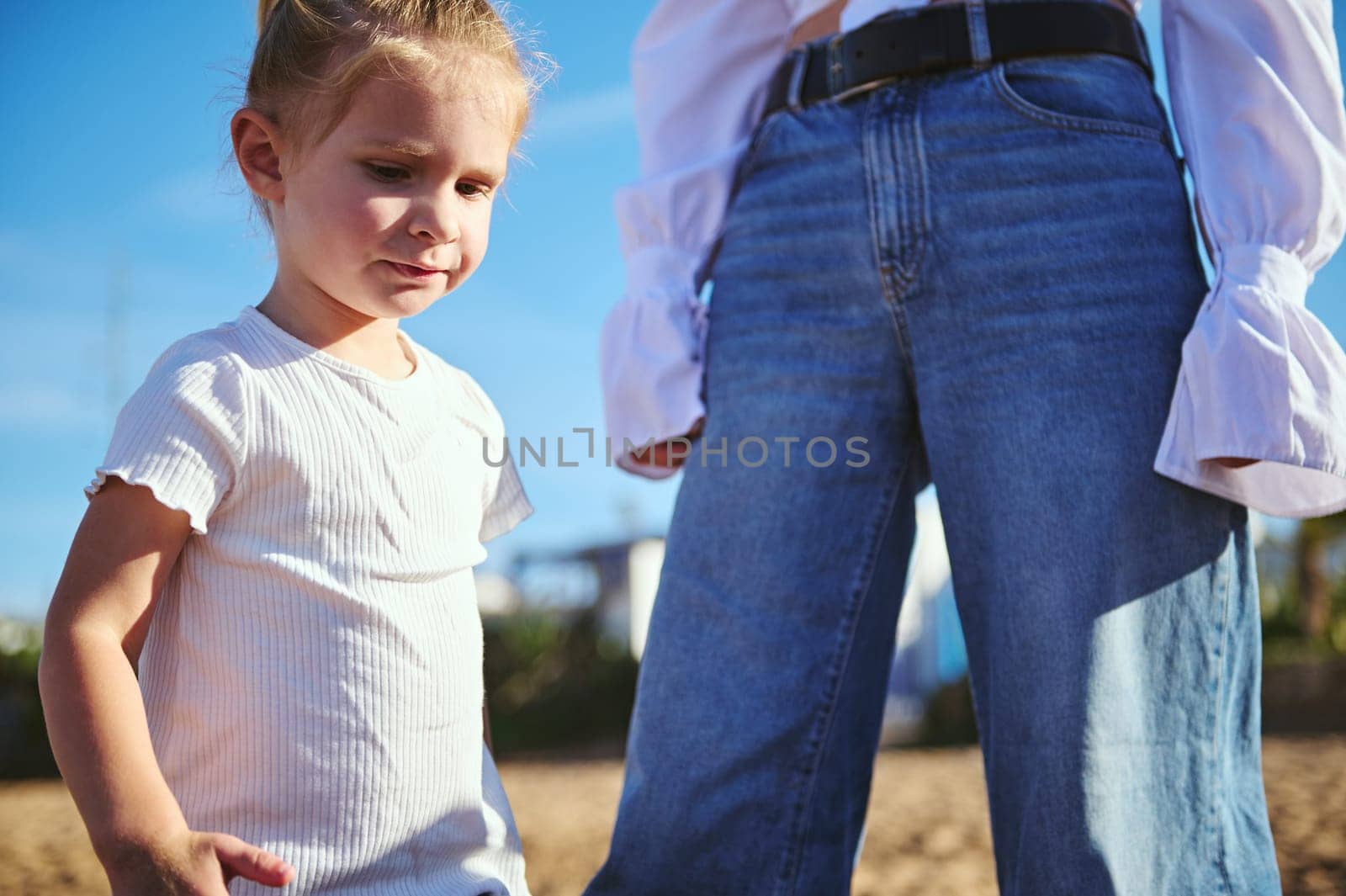 Close-up lifestyle portrait of a mother and daughter walking together on the beach