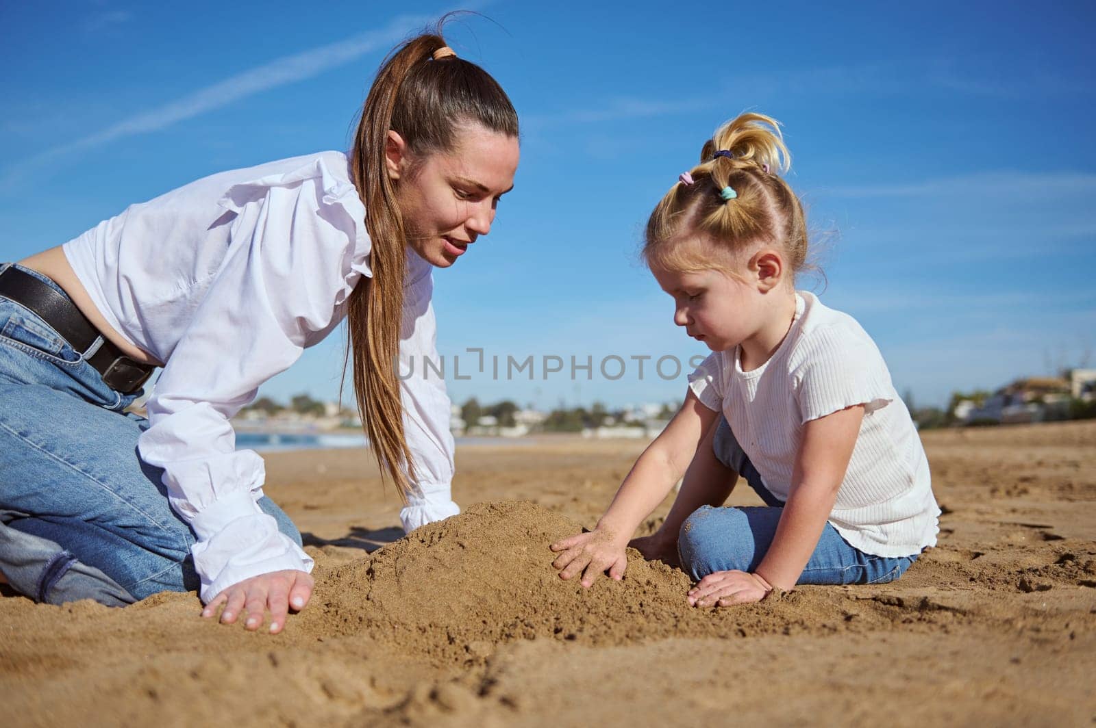 Close up portrait of happy of mother and daughter building castle in sand at beach. Family lifestyle, Leisure activity, People. Vacations