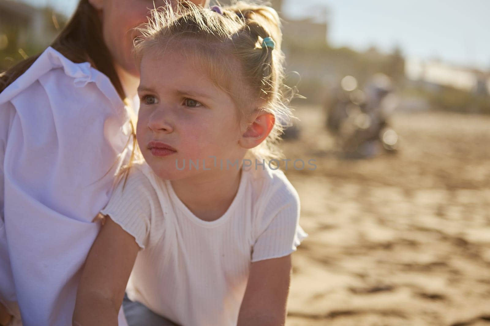 Cute baby girl with her loving mother on the sandy each by artgf